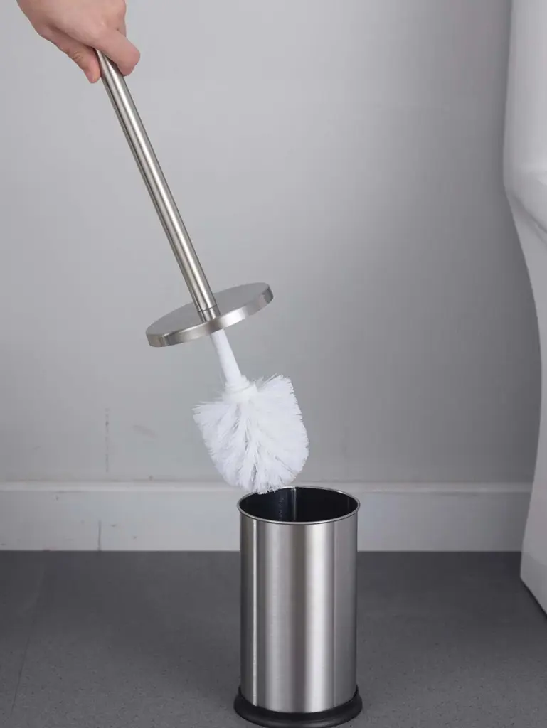 Brosse WC inox avec poignée longue et poils blancs, dans son support métallique.