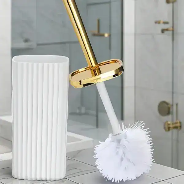 Brosse WC avec manche doré et poils blancs, dans un support blanc, pour salle de bain.