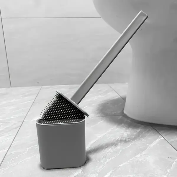 Brosse toilette flexible grise dans son support, près d'un WC.