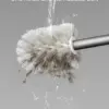 Brosse WC boule blanche en train d'être rincée, éliminant les résidus.
