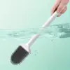 Brosse WC blanche avec poignée longue, utilisée dans l'eau pour nettoyage.