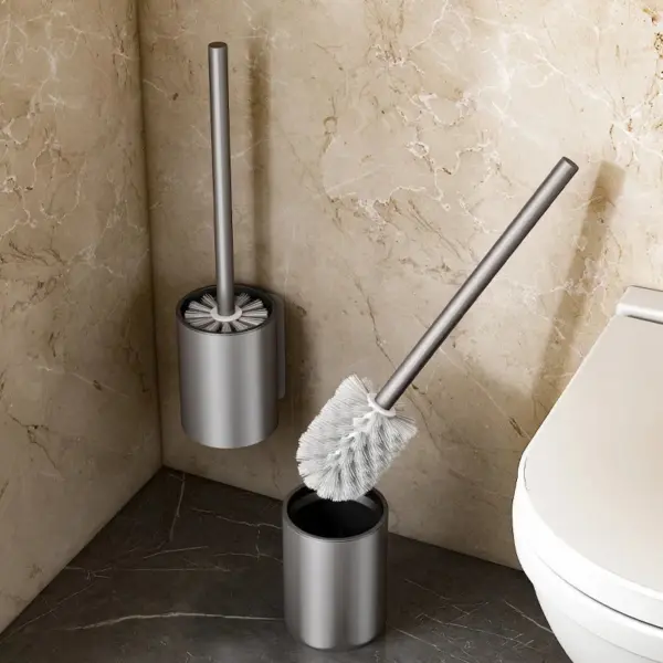 Brosse WC boule en métal avec poignée longue, présentée dans un porte-brosse chromé près d'un WC.