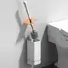 Brosse WC suspendue design avec poignée blanche et support mural blanc, proche d'un WC.